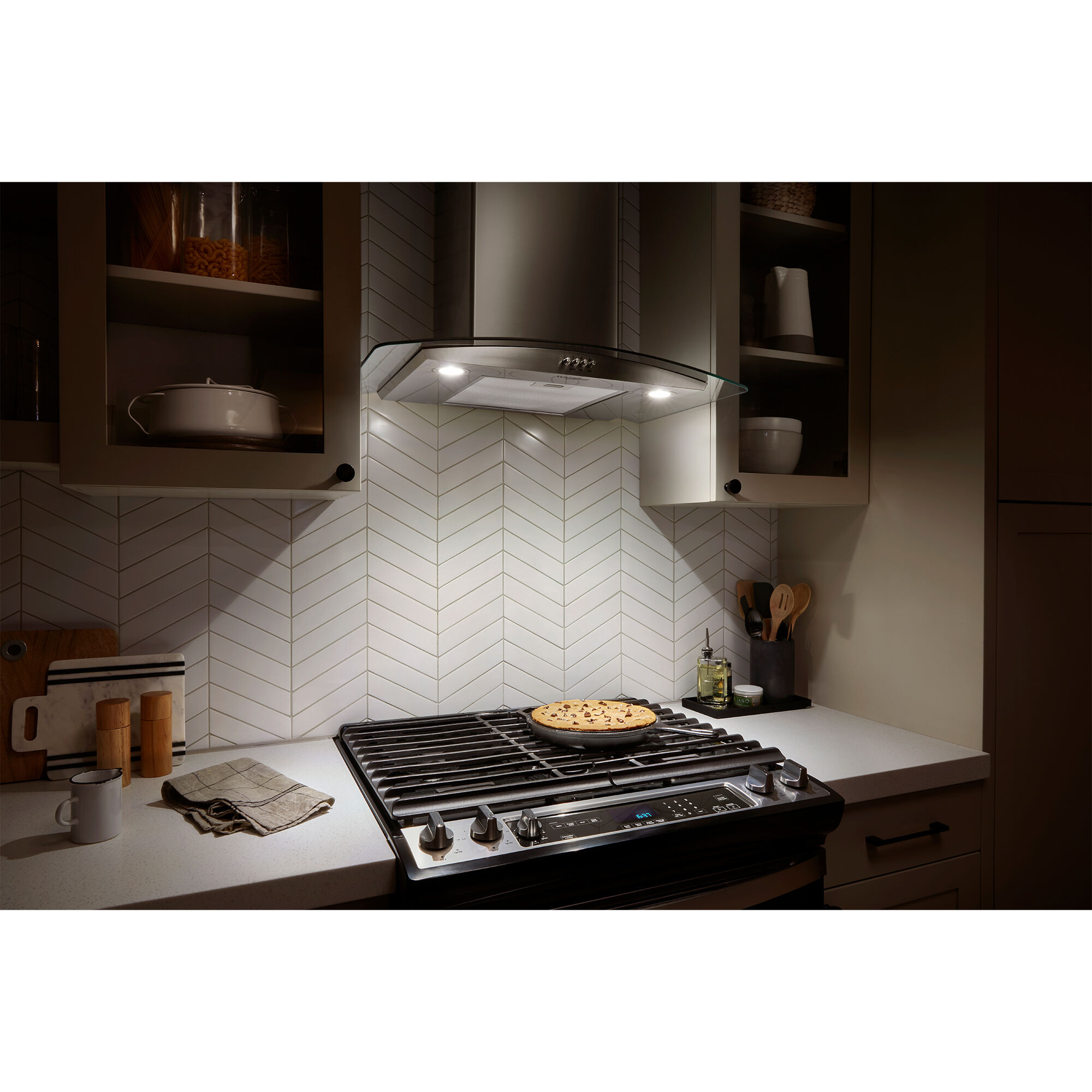 Whirlpool WVW51UC0LS stainless steel range hood with LED lights on, illuminating the cooktop surface below.