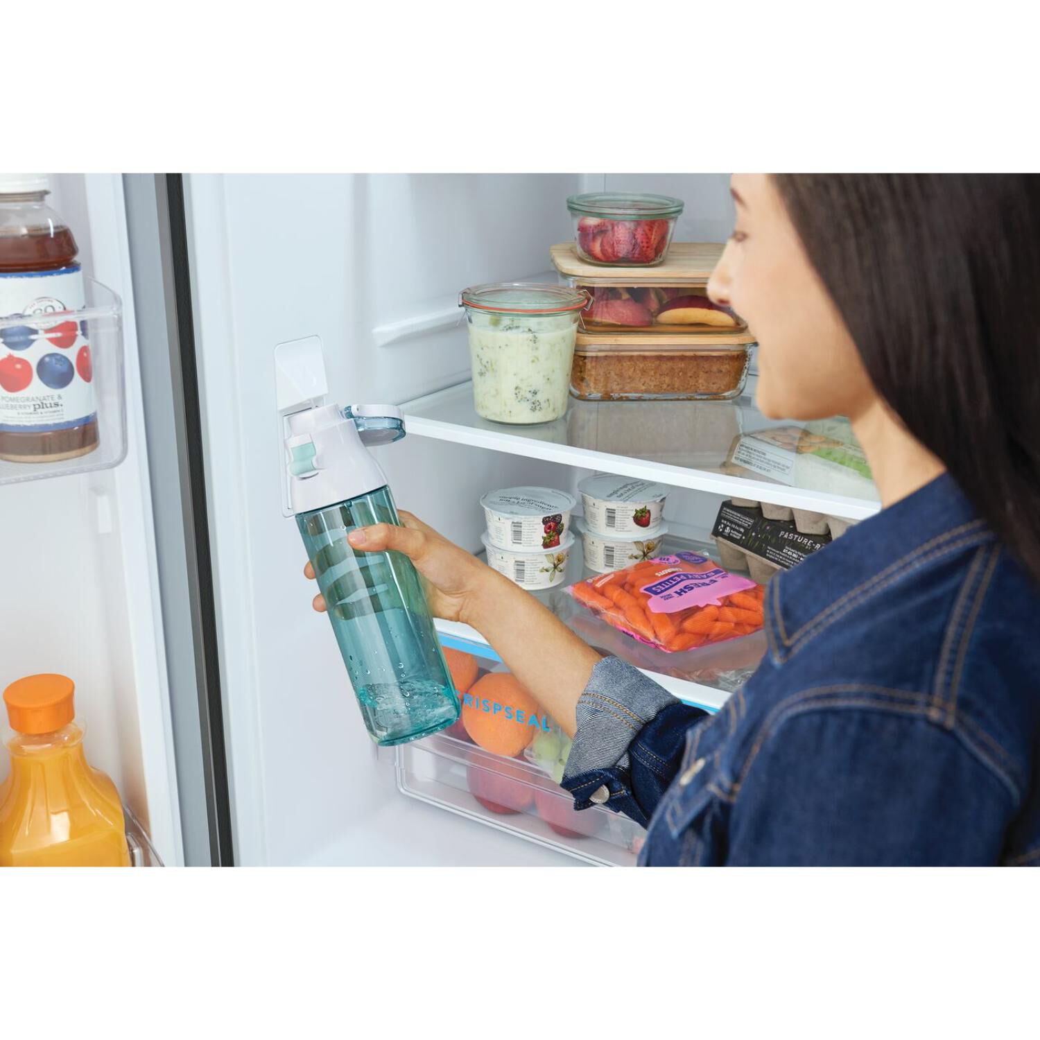 Interior view of FRFG2033AV showing woman with water bottle using the internal water dispenser.
