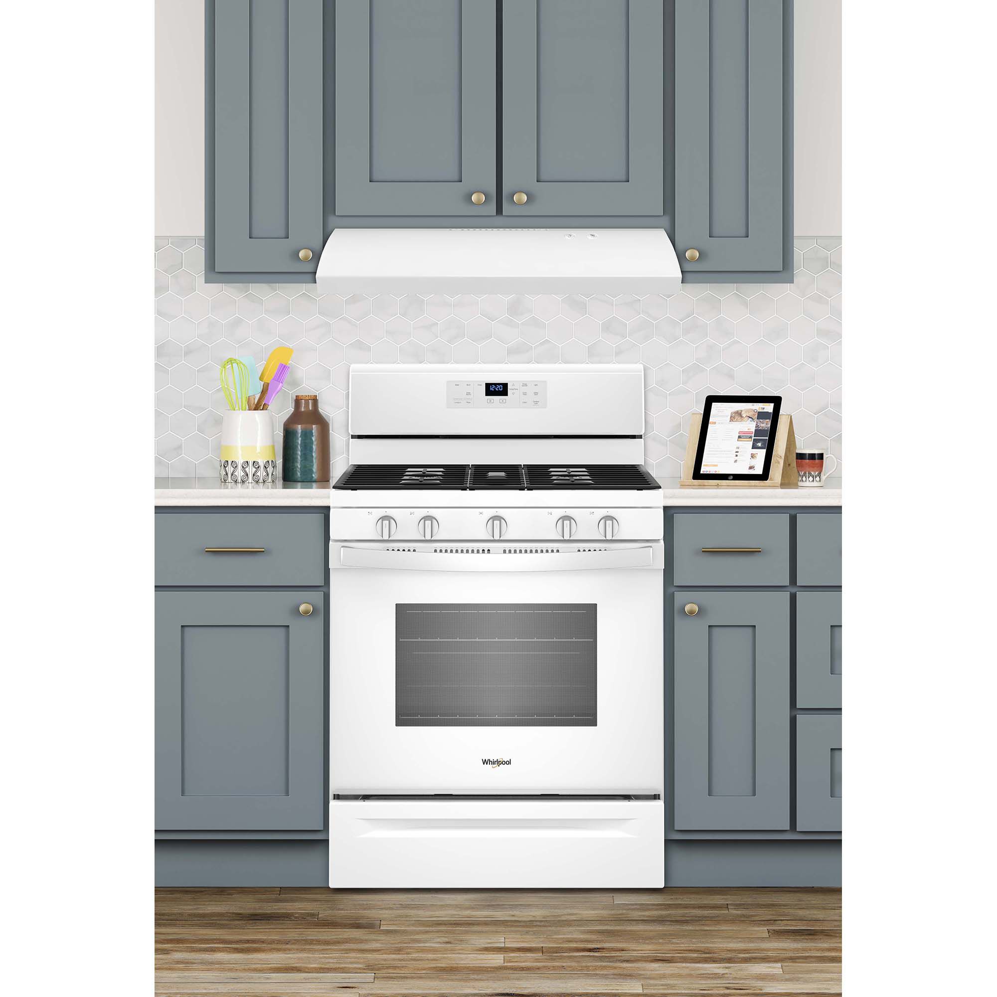 Whirlpool UXT2030ADW white undercabinet range hood installed above a stovetop, illuminating the cooking surface below.