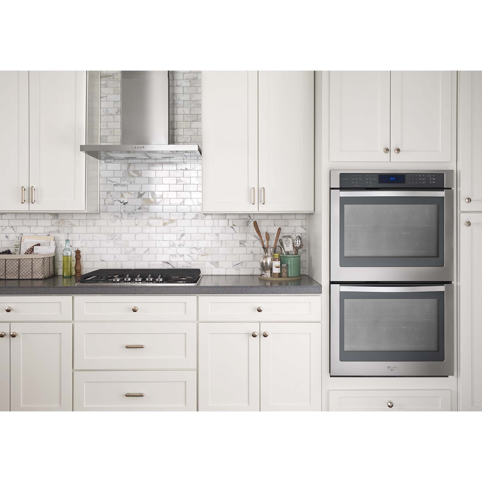 Whirlpool WVW57UC6FS stainless steel flat range hood shown above a kitchen cooktop in a modern kitchen setting.