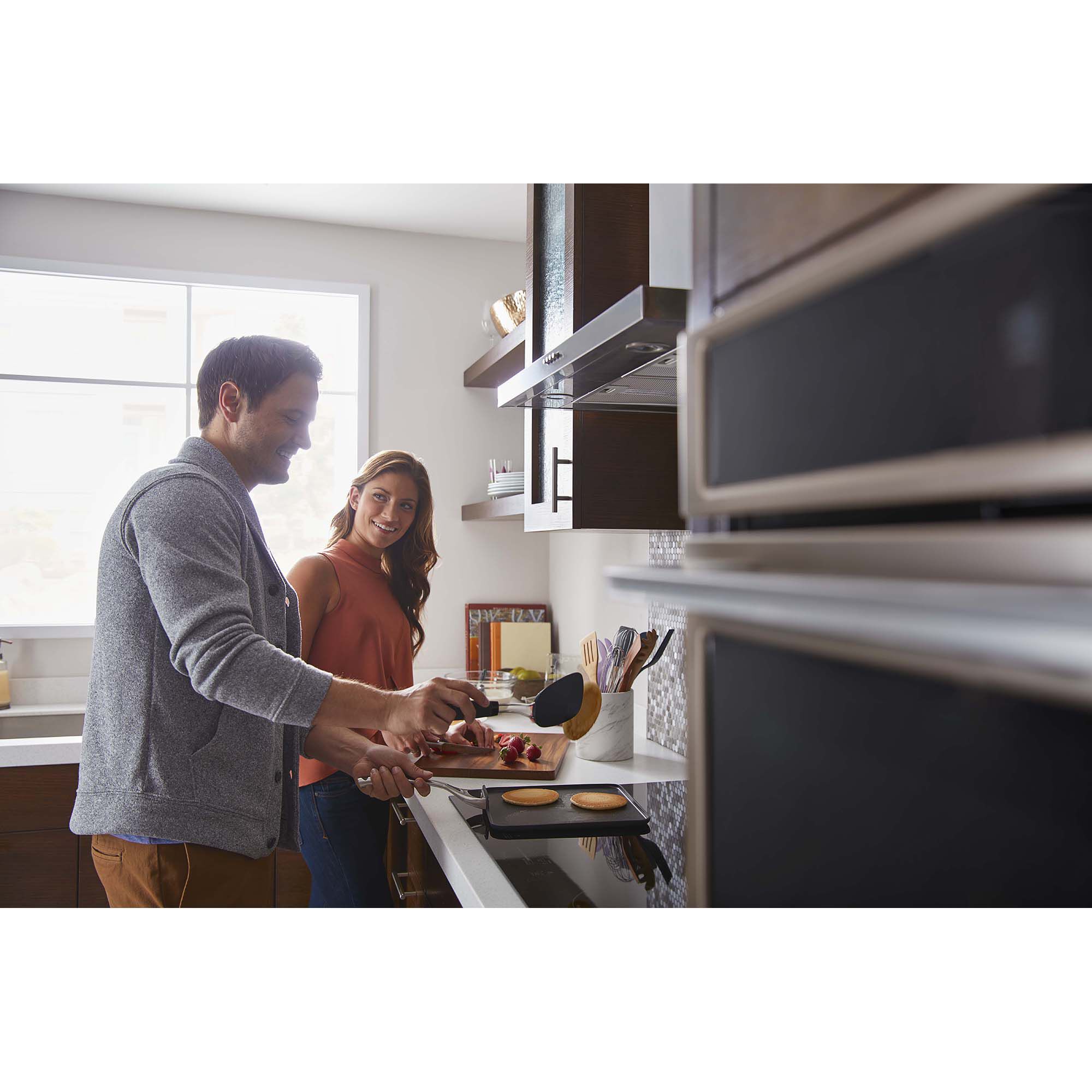 Close-up of the Whirlpool WVW57UC0FS range hood ventilation system operating above a gas range with steam rising from a pot.
