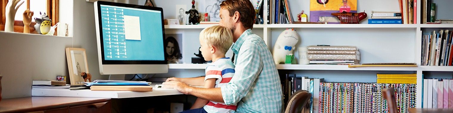 Father and son sitting at desk working on computer together