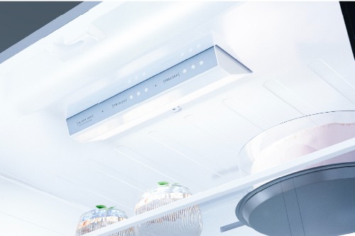 Close-up of Midea French door refrigerator's interior ceiling featuring a sleek LED lighting panel with touch control display and temperature settings, illuminating the upper storage compartment.