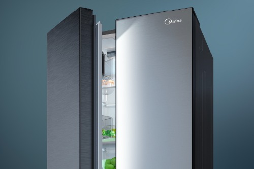 Midea side-by-side refrigerator with both doors open, showcasing stainless steel exterior finish and illuminated interior shelving with fresh produce visible, set against a teal background.
