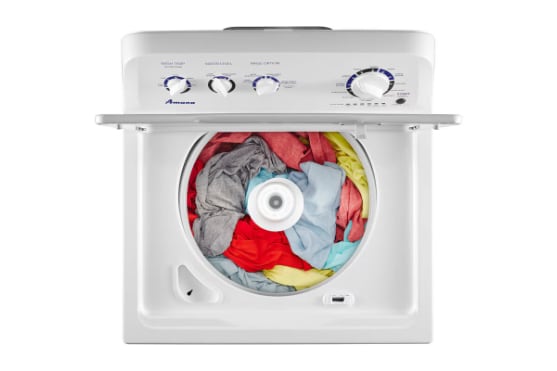 Top-down view of Amana white top-load washer with lid open showing agitator and colorful laundry load inside, with control panel featuring dials and buttons visible.