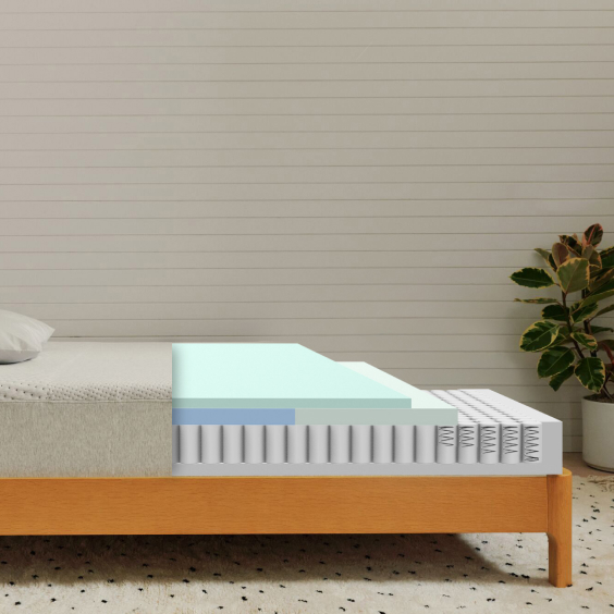 Cutaway view of Casper Dream mattress showing three internal layers: mint green top comfort layer, blue middle support layer, and white pocketed coil base with individual springs, displayed on wood platform bed frame against white shiplap wall.