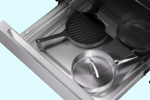 Midea oven storage drawer open with a grill pan and a lidded frying pan inside.