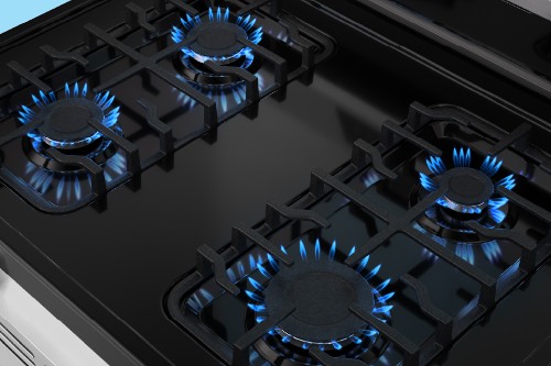 Midea oven cooktop with four gas burners lit by blue flames.