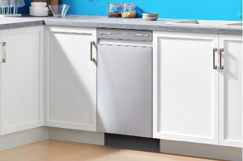Midea 18-inch stainless steel front control dishwasher installed between white cabinets with a gray countertop.