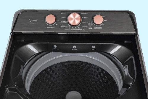 Top-down view of Midea washer showing deep tub with black interior, textured drum surface, and rose gold control panel with three rotary dials.