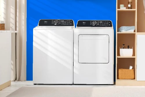 Midea white top load washer and matching dryer side by side in modern laundry room with blue accent wall and organized shelving