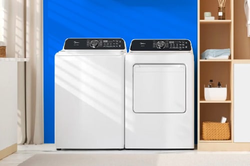 Midea white top load washer and matching dryer side by side in modern laundry room with blue accent wall and organized shelving