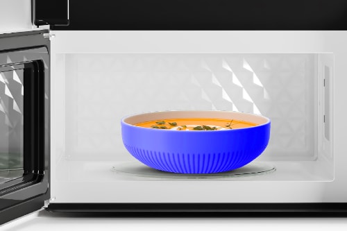 Interior view through microwave door showing blue bowl with steaming food on turntable, demonstrating cooking capacity and even heating inside spacious 1.7 cu. ft. cavity.