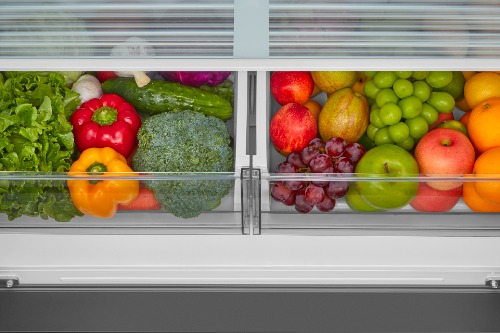 Close-up of the crisper drawers in Midea Refrigerator Model MRF23I5AST, filled with fresh vegetables and fruit including lettuce, peppers, broccoli, grapes, pears, apples, and oranges.