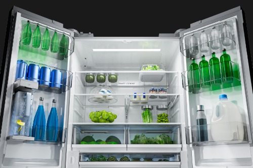 Midea MRF27I6BST French door refrigerator open, showing spacious interior with multiple shelves stocked with beverages, fresh produce, and condiments, illuminated by interior lighting.