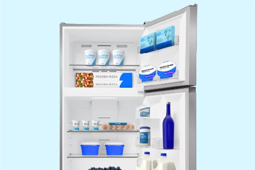 Interior view of the Midea 18 cu. ft. Top-Freezer Refrigerator model MRT18D3B showing organized storage with frozen pizza, dairy, eggs, beverages, and milk inside adjustable glass shelves and door bins.