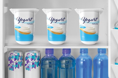 Interior shelves of Midea mini fridge showing three yogurt containers on top shelf and decorative beverage cans plus four water bottles organized on lower shelf.