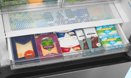 Open deli drawer in Midea refrigerator displaying organized cheese varieties and deli meats in clear compartments with temperature-controlled storage for freshness.