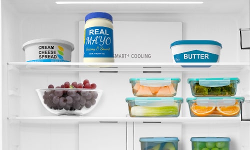 Midea refrigerator's spillproof glass shelves with Smart Cooling technology, organized with dairy products on top shelf and fresh produce in clear containers below.