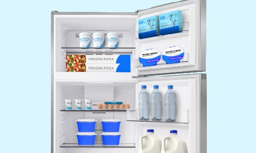 Interior view of Midea top-freezer refrigerator with both doors open showing top freezer compartment with frozen foods and bottom fresh food section with beverages and storage containers.