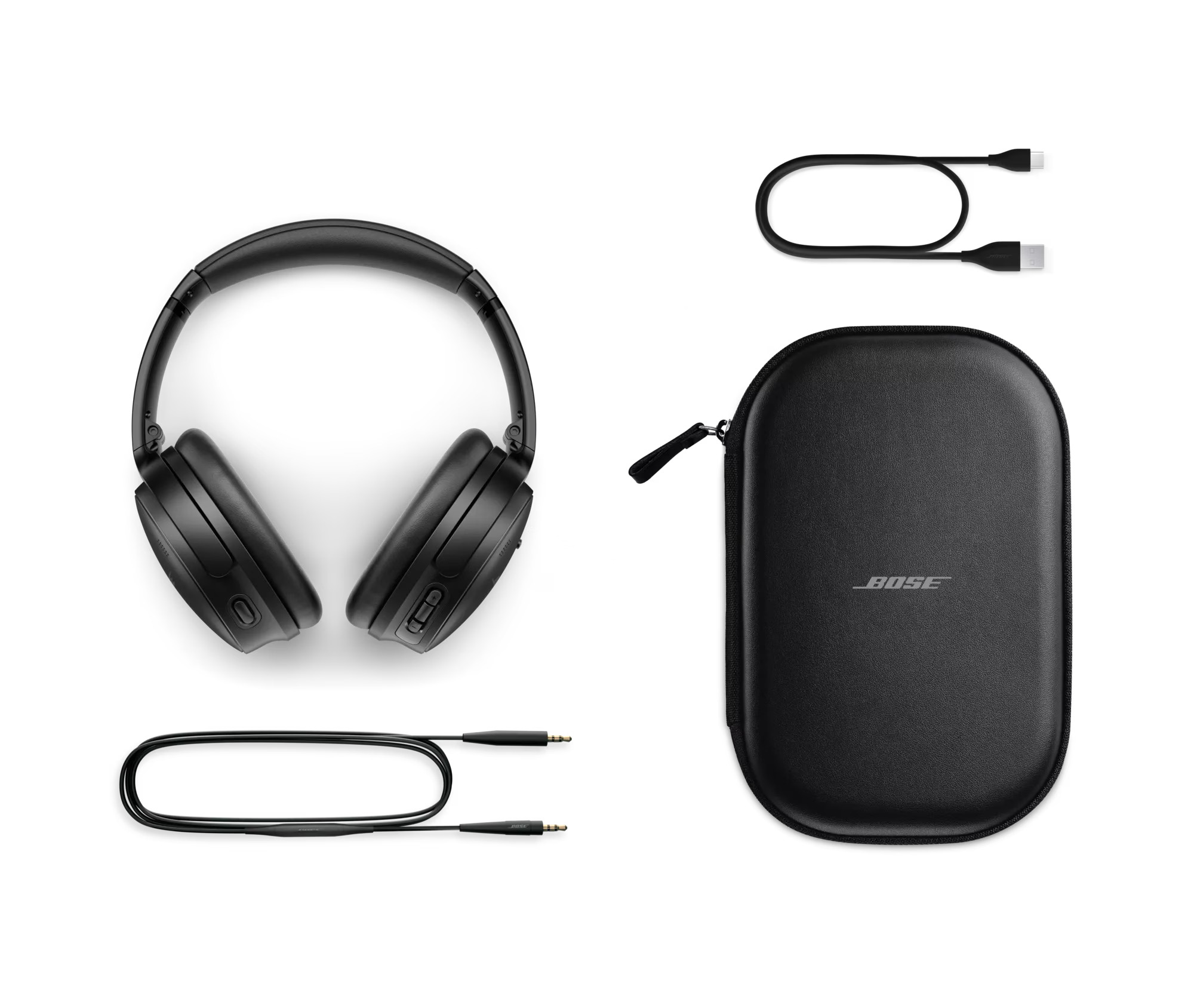Bose QuietComfort QCHEADPHNBLK package contents showing black over-ear headphones with control buttons, hard-shell carrying case with Bose logo, USB-C charging cable, and 3.5mm audio cable, arranged on white background
