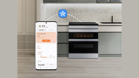 Smartphone displaying Samsung SmartThings app controlling double oven range remotely, with range visible in background showing cookies baking and smart connectivity icon above.