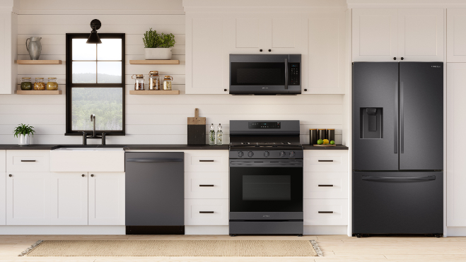 Samsung NX60A6511SG black stainless steel gas range installed in modern kitchen with white cabinets, matching black stainless appliances including refrigerator, dishwasher, and microwave