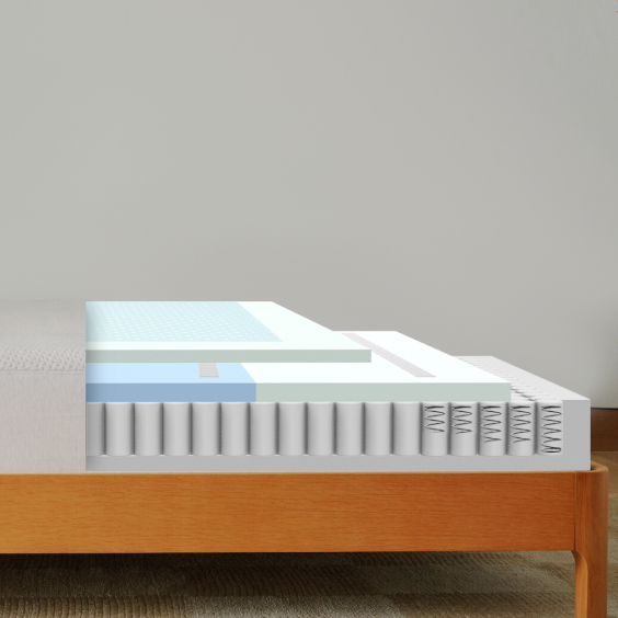Cutaway view of Casper Snow mattress showing layered construction with light blue cooling top layer, white comfort foam layers, blue support layer above pocketed coil base with individual springs, displayed on wood bed frame.