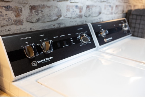 Speed Queen TR3006WN top load washer in a laundry room, showing durable construction, rotary controls, and a clean, accessible design suitable for everyday use.