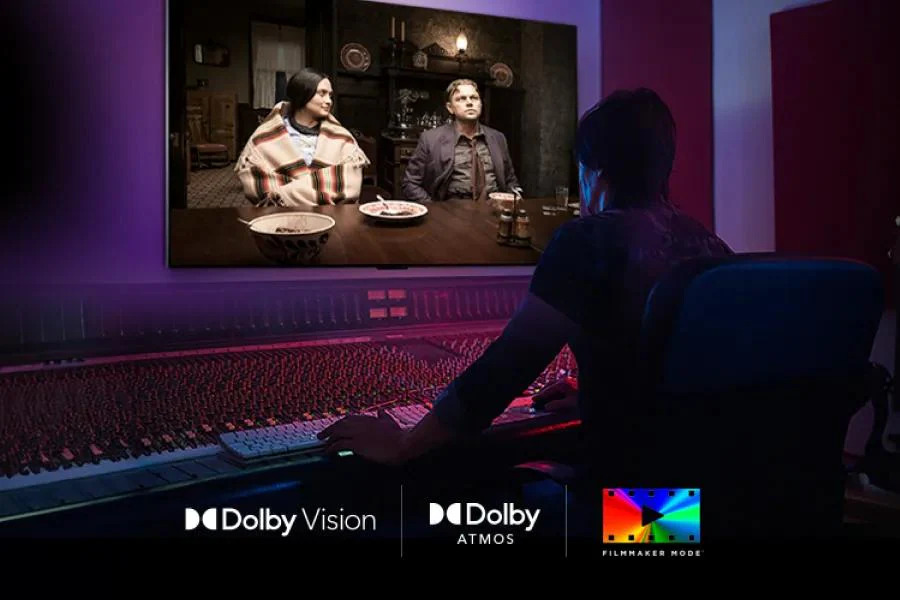 Person at a mixing console watching a film on an LG TV in a darkened studio, with Dolby Vision, Dolby Atmos, and Filmmaker Mode logos displayed below.