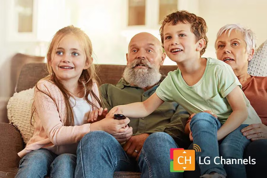 Two children and two grandparents sitting together on a sofa watching TV, with the LG Channels logo in the corner.