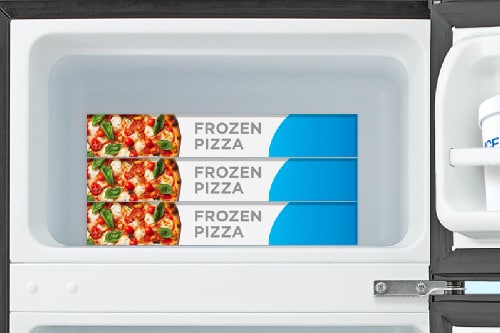 Close-up of compact refrigerator freezer compartment with door open, showing white interior holding three frozen pizza boxes with storage capacity for frozen foods.