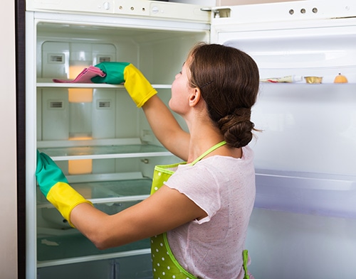 lady cleaning inside of refrigerator 