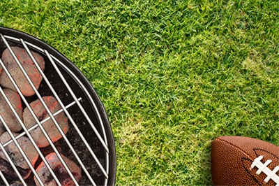 Grill on Green Grass with Football Nearby