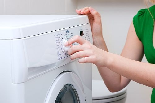 Woman operating Washing Machine control dial 