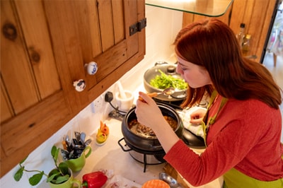 Woman Tasting Chili From Slow Cooker