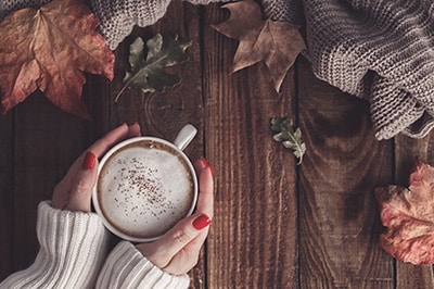 Two Hands Holding Cocoa on an Autumnal Background