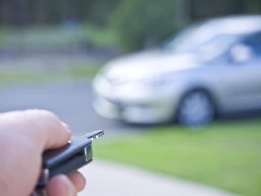 Hand Pointing Key Fob at Distant Car