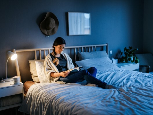 Woman Lounging in Bed Reading a Book in the Evening