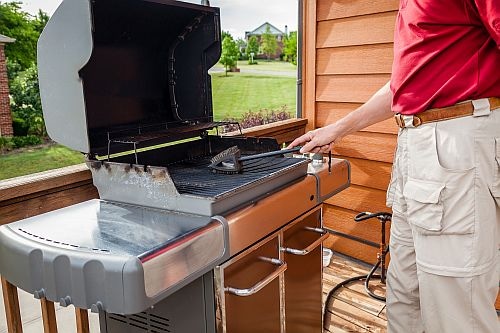 Man cleaning BBQ grill with wire brush 