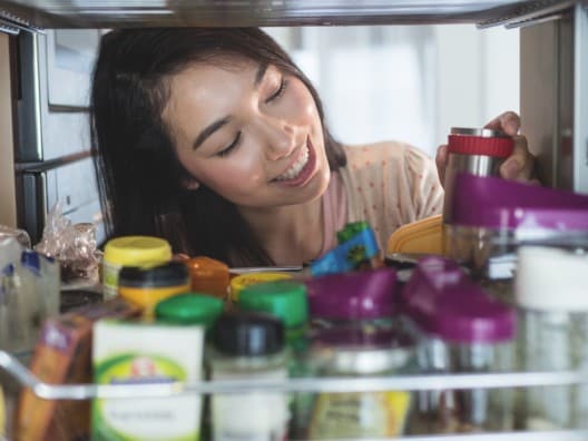 Woman Rummaging Through Spice Rack in Pantry