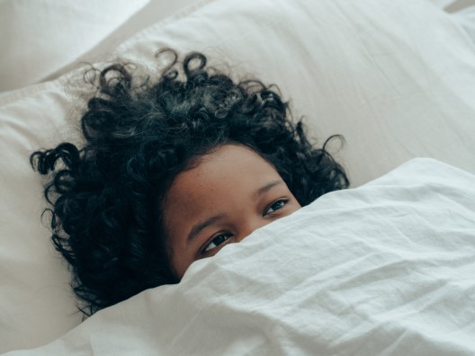 Woman of Color in Bed Covered with Blanket Up to Eyes