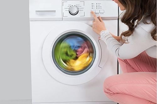 Woman turning on front 
load washing machine 