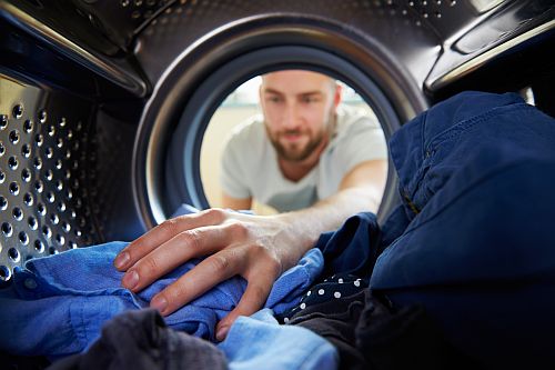Man loading a dryer with clothes 