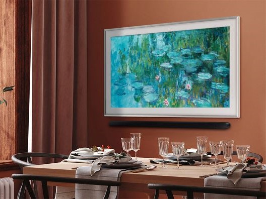 Elegant dining table set for four people with a Samsung Frame on the wall displaying what appears to be one of Monet's Water Lillies