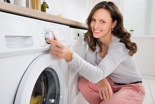 Woman kneeling next to washer 