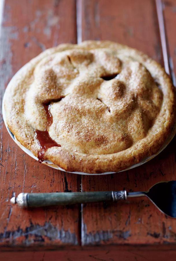 Apple Pie resting on wooden table with pie cutter