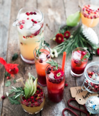 Festive Holiday Drinks Garnished with Cranberries and Rosemary on Distressed Wood Table