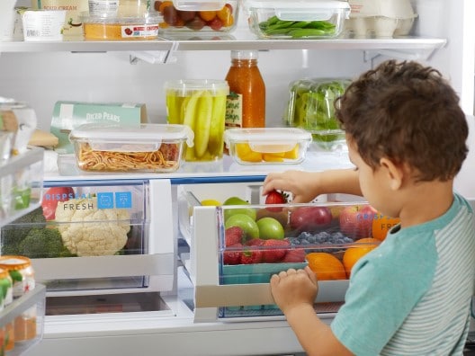 Small Boy Reaching Into Crisper for a Piece of Fruit