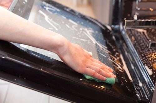 Person's Arm Scrubbing Oven Interior with Soap